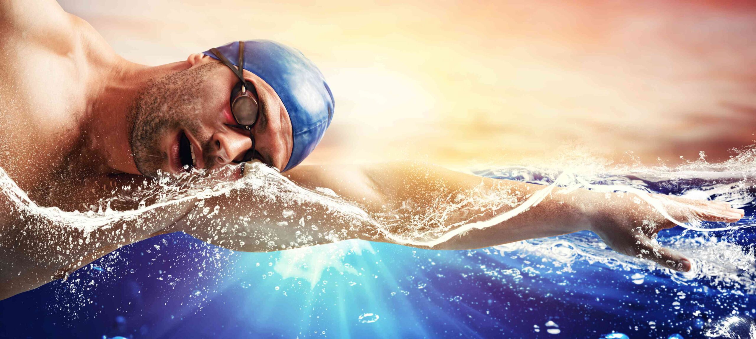 Schwimmer vor Sonnenuntergang mit blauer Kappe und Schwimmbrille