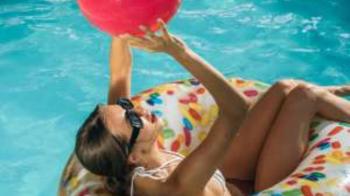 Eine Frau mit Sonnenbrille liegt entspannt in einem Schwimmring auf dem Wasser